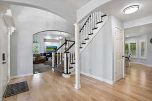 Entryway featuring light wood-style flooring, stairway, and arched walkways