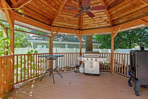 Wooden terrace featuring a ceiling fan, a gazebo, area for grilling, and a fenced backyard