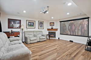 Home theater room with light wood-style flooring, recessed lighting, and a glass covered fireplace