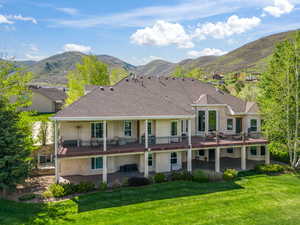 Rear view of property featuring stucco siding, a patio area, a yard, and a deck with mountain view