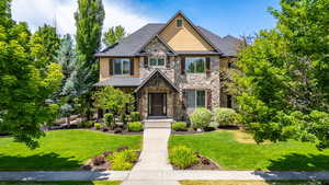 Craftsman house with stone siding, stucco siding, and a front yard