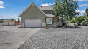 View of front facade with stucco siding, stone siding, driveway, a garage, and french doors