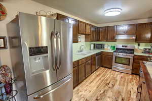 Kitchen featuring appliances with stainless steel finishes, under cabinet range hood.