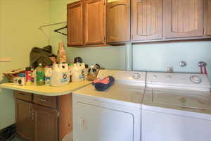 Laundry area featuring washing machine and dryer and cabinets