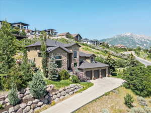 View of front of home with stone siding, concrete driveway, a mountain view, and a garage