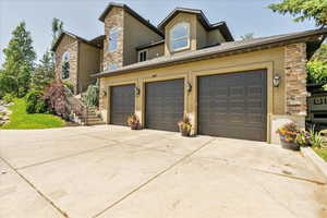 View of front of house with stone siding, driveway, stucco siding, and stairway