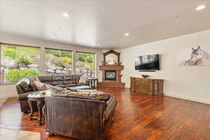 Living area featuring wood finished floors, a glass covered fireplace, and recessed lighting