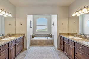 Bathroom featuring two vanities, a bath, and tile patterned floors