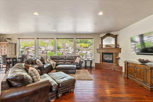 Living area with healthy amount of natural light, a glass covered fireplace, dark wood-type flooring, and recessed lighting