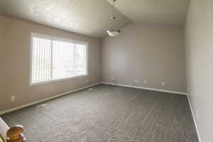 Unfurnished room with carpet flooring and lofted ceiling