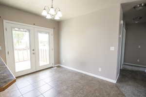 Entryway with french doors, tile patterned floors, and a chandelier