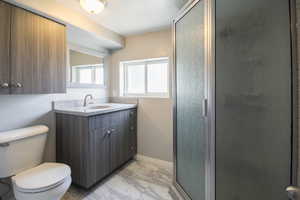Full bathroom featuring marble look tiles, vanity, and a shower stall