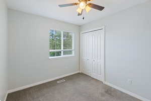 Unfurnished bedroom with carpet floors, a closet, and ceiling fan