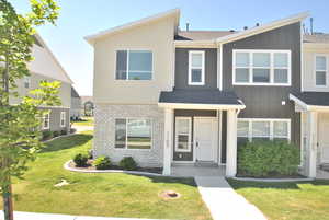 Townhome / multi-family property with board and batten siding, a shingled roof, and a front yard