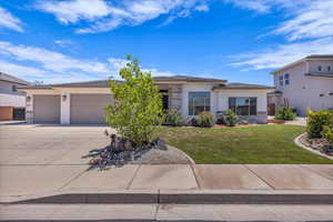 View of front facade with stucco siding, driveway, an attached garage, and a front yard