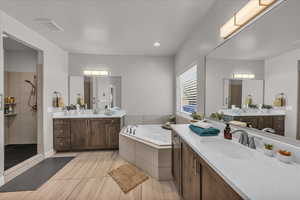 Bathroom featuring a tile shower, two vanities, and a tub with jets
