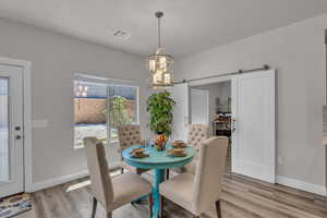 Dining room with a chandelier, a barn door, and light wood-style flooring