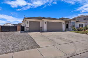 Prairie-style home featuring a gate, an attached garage, stone siding, stucco siding, and driveway
