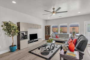 Living room featuring a ceiling fan, light wood-type flooring, and recessed lighting