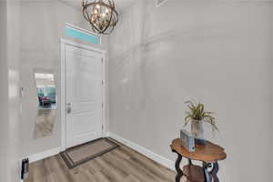 Foyer featuring light wood finished floors and a chandelier