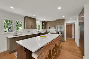 Kitchen with stainless steel appliances, open shelves, light wood-style flooring, a breakfast bar, and recessed lighting