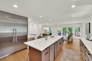 Kitchen with stainless steel built in fridge, recessed lighting, light wood finished floors, a breakfast bar, and light countertops
