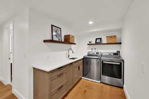 Washroom with independent washer and dryer, cabinet space, light wood finished floors, and recessed lighting