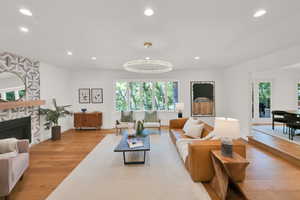 Living area with recessed lighting, wood finished floors, and a stone fireplace