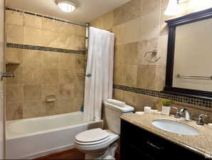 Master bathroom with tile walls, shower / bath combination with curtain, vanity, and decorative backsplash