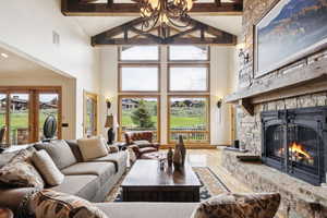 Living area with high vaulted ceiling, beam ceiling, a fireplace, and wood finished floors