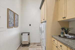 Laundry room featuring washer and dryer, light stone finish flooring, and cabinet space