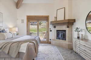 Carpeted bedroom with a fireplace, access to exterior, and beam ceiling