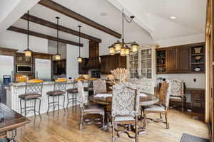 Dining room featuring light wood finished floors, beamed ceiling, and high vaulted ceiling