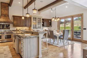 Kitchen with decorative backsplash, hanging light fixtures, appliances with stainless steel finishes, light wood finished floors, and a kitchen breakfast bar