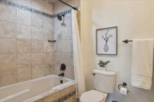 Bathroom featuring tiled shower / bath and toilet