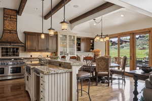Kitchen with appliances with stainless steel finishes, a kitchen breakfast bar, open shelves, tasteful backsplash, and an island with sink
