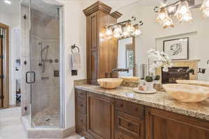 Full bathroom with double vanity, a stall shower, and light tile patterned floors
