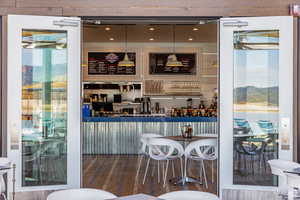 Community bar area with wood finished floors and decorative light fixtures
