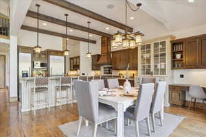 Dining area featuring beamed ceiling, light wood-style flooring, and recessed lighting