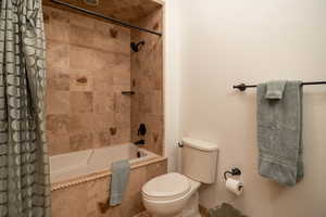 Bathroom with tiled shower / bath and toilet