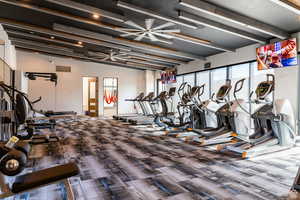 Workout area with carpet floors, beam ceiling, and a ceiling fan