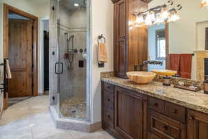 Bathroom with a shower stall, vanity, tile patterned flooring, and a fireplace