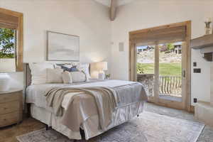 Carpeted bedroom featuring access to exterior and beam ceiling