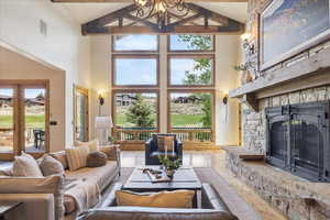 Living room with beam ceiling, high vaulted ceiling, wood finished floors, and a fireplace