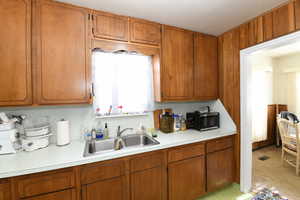 Kitchen with light countertops, stainless steel microwave, and brown cabinets