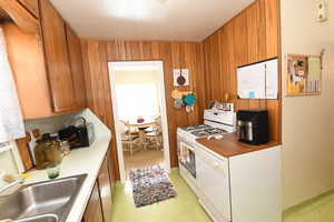 Kitchen with white appliances, light countertops, brown cabinets, and wood walls