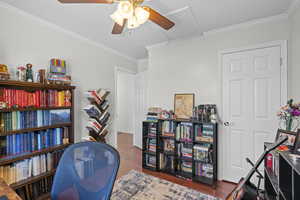 Office space with a ceiling fan, wood finished floors, and crown molding
