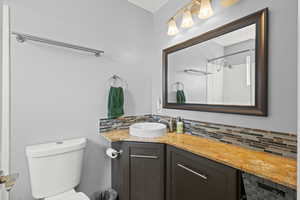Full bathroom with tasteful backsplash, vanity, and a shower