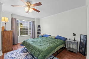 Bedroom featuring wood finished floors, a textured ceiling, crown molding, and a ceiling fan
