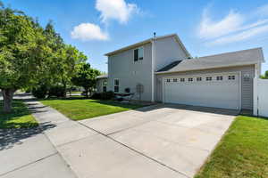 View of side of property featuring driveway, a lawn, and a garage